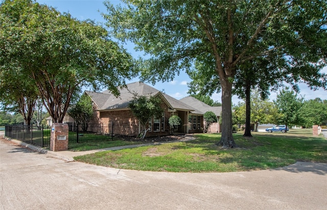 view of front facade with a front yard, brick siding, and a fenced front yard