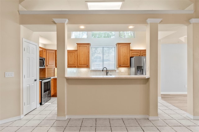 kitchen featuring ornate columns, decorative backsplash, appliances with stainless steel finishes, and light countertops