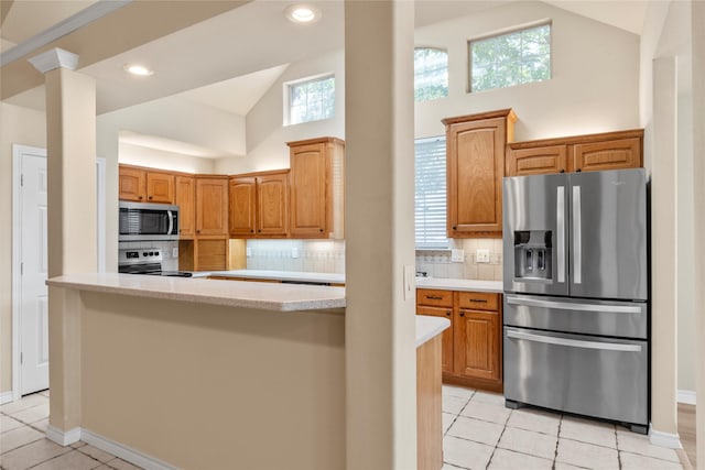 kitchen with decorative backsplash, light tile patterned flooring, appliances with stainless steel finishes, and high vaulted ceiling