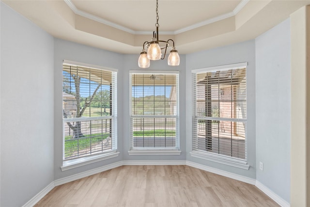 unfurnished dining area featuring a raised ceiling, light wood-style flooring, a notable chandelier, and a wealth of natural light