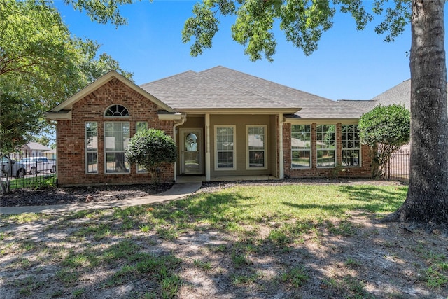 single story home featuring brick siding, a shingled roof, a front lawn, and fence