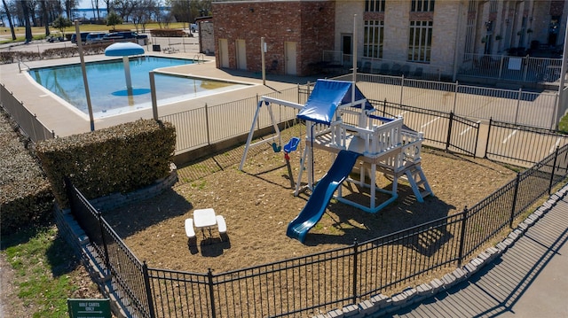 view of swimming pool with playground community and fence