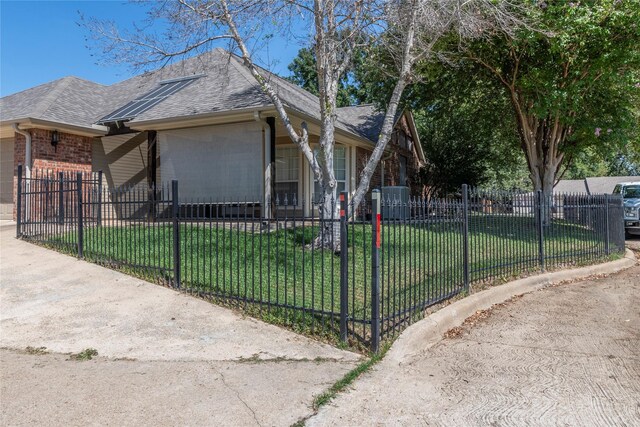 view of home's exterior featuring an attached garage, a yard, a fenced front yard, and roof with shingles