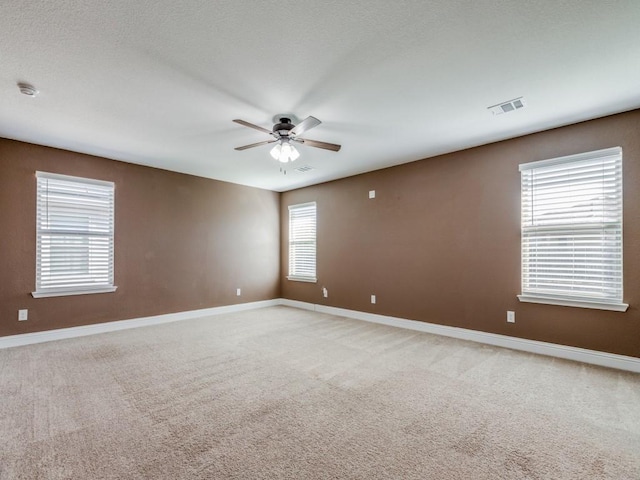 empty room featuring visible vents, baseboards, light colored carpet, and a ceiling fan