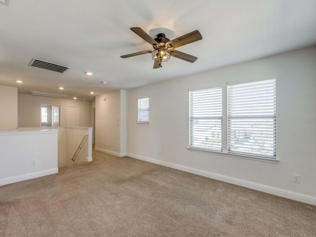 spare room featuring light carpet, visible vents, recessed lighting, and baseboards