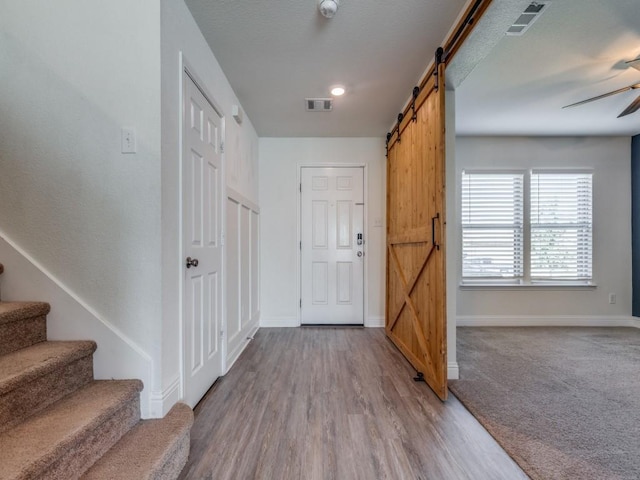 entrance foyer featuring visible vents, ceiling fan, stairway, and a barn door