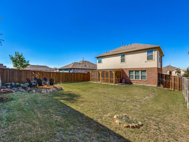 back of house featuring a yard, brick siding, a fenced backyard, and a sunroom