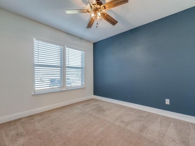 carpeted empty room featuring a ceiling fan and baseboards