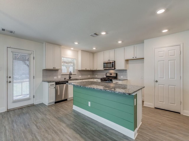 kitchen with visible vents, light wood-style flooring, a sink, appliances with stainless steel finishes, and white cabinets