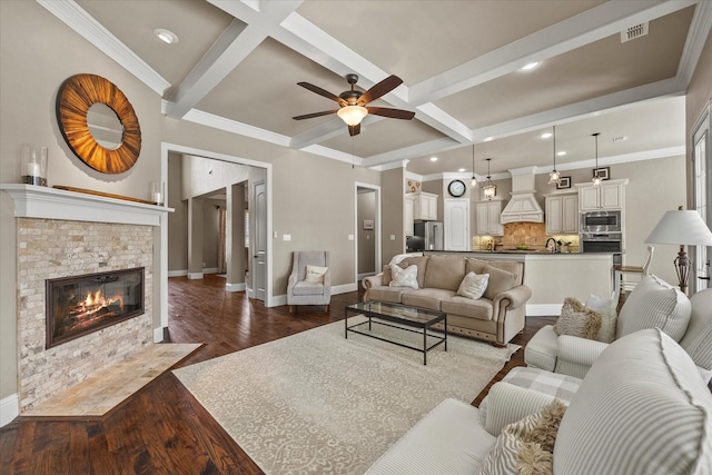 living area featuring dark wood finished floors, beam ceiling, a ceiling fan, and baseboards