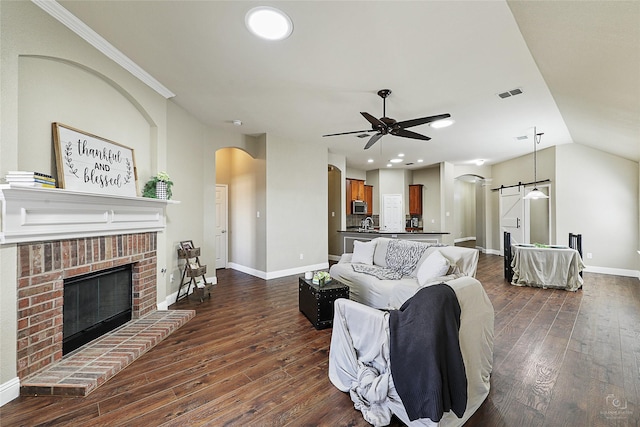 living room featuring a ceiling fan, visible vents, baseboards, dark wood finished floors, and arched walkways