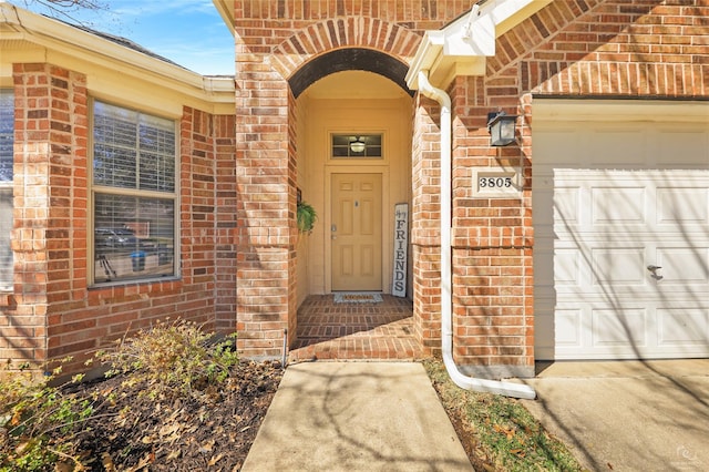 property entrance with concrete driveway, an attached garage, and brick siding