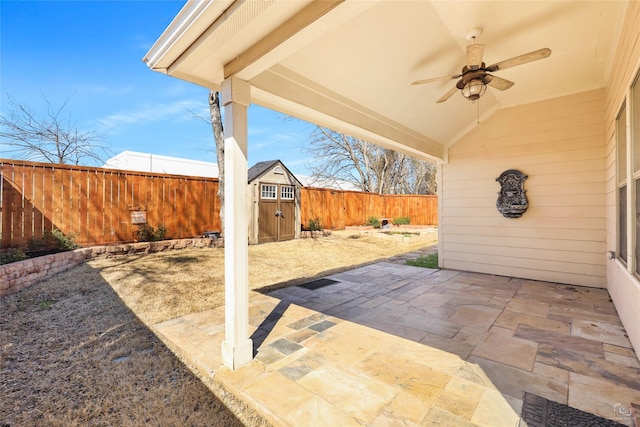 view of patio with an outbuilding, a storage shed, a fenced backyard, and a ceiling fan