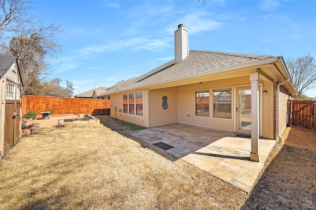 rear view of property with a fenced backyard, a chimney, a shingled roof, and a patio