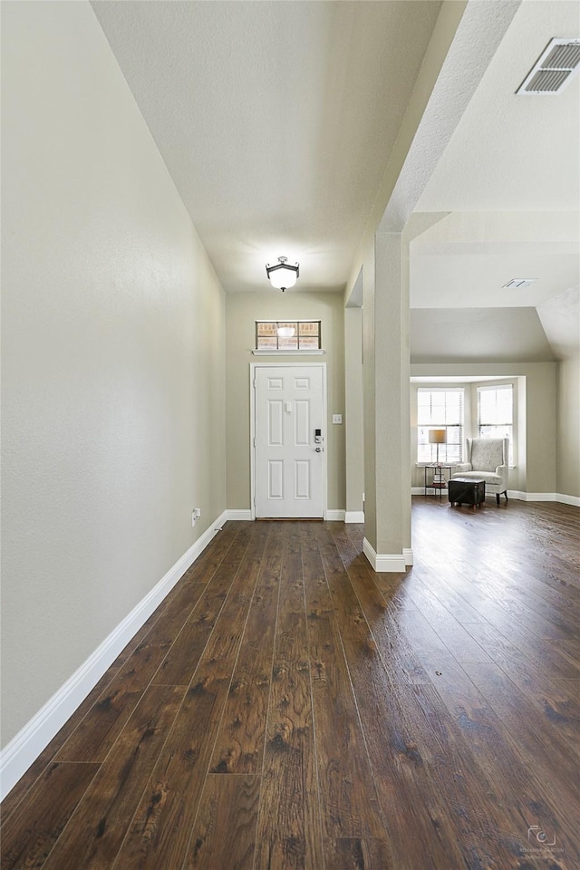 entryway with baseboards, visible vents, and dark wood-style flooring