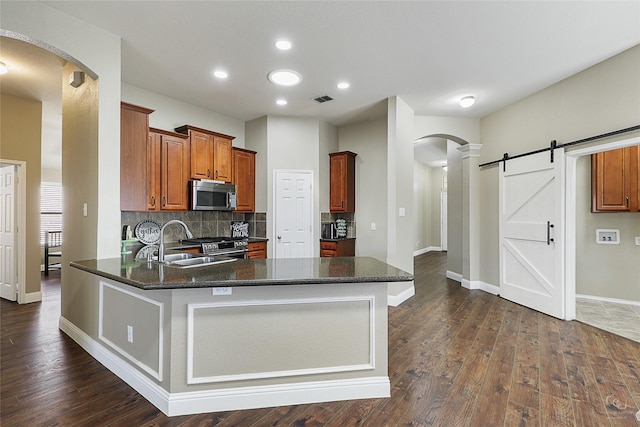 kitchen with visible vents, a peninsula, arched walkways, stainless steel appliances, and a sink