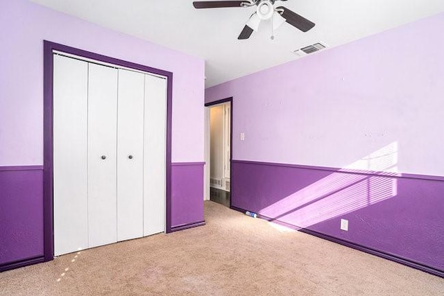 unfurnished bedroom featuring a closet, visible vents, carpet flooring, and ceiling fan