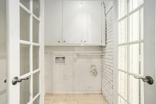 clothes washing area with french doors, cabinet space, hookup for a washing machine, and brick wall