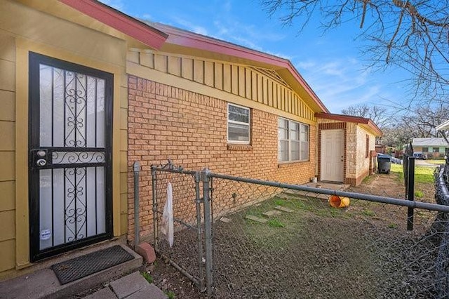 view of exterior entry with brick siding and fence