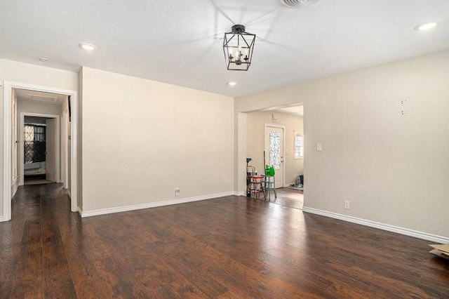 empty room with a notable chandelier, recessed lighting, wood finished floors, and baseboards