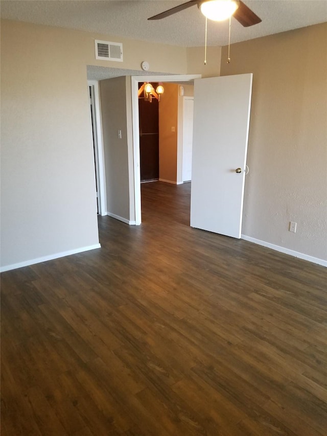 unfurnished room with visible vents, dark wood-type flooring, baseboards, ceiling fan with notable chandelier, and a textured ceiling
