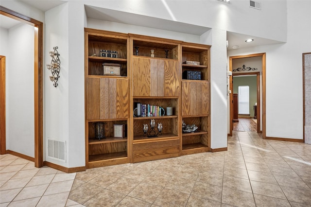 interior space featuring light tile patterned flooring, visible vents, and baseboards