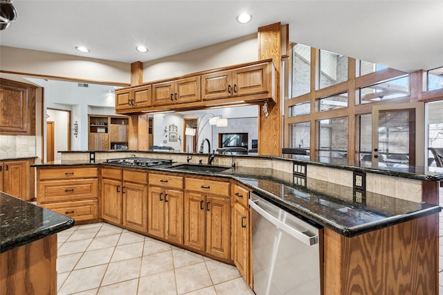 kitchen with a sink, appliances with stainless steel finishes, a peninsula, brown cabinetry, and decorative backsplash