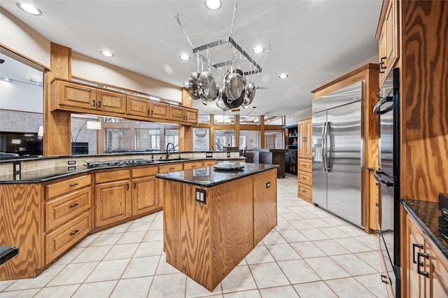 kitchen with a notable chandelier, a sink, a center island, stainless steel appliances, and light tile patterned flooring