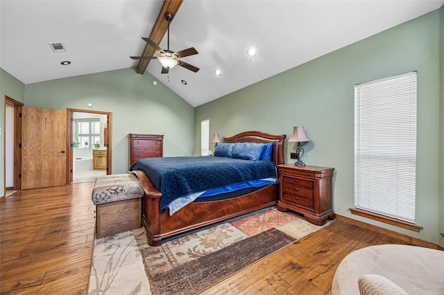 bedroom featuring a ceiling fan, visible vents, lofted ceiling with beams, wood-type flooring, and connected bathroom