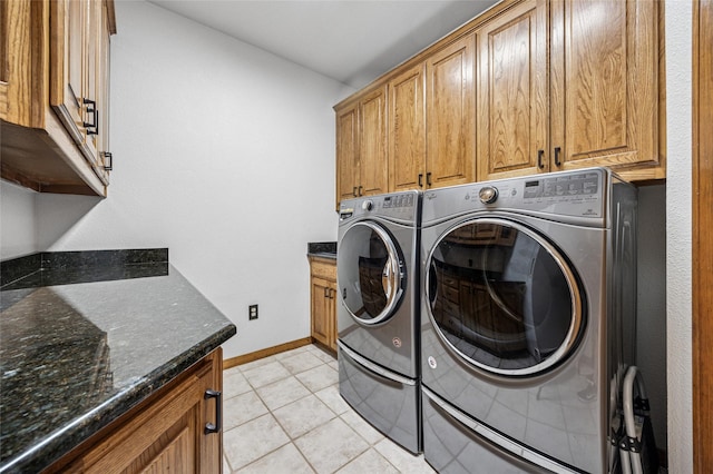 laundry room featuring light tile patterned flooring, washing machine and dryer, cabinet space, and baseboards