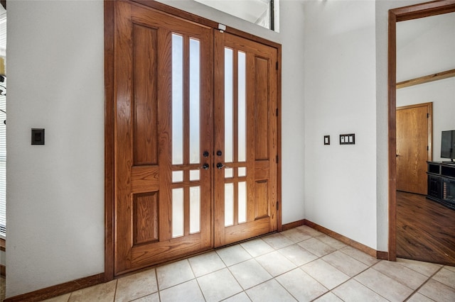 entrance foyer with light tile patterned floors, french doors, and baseboards