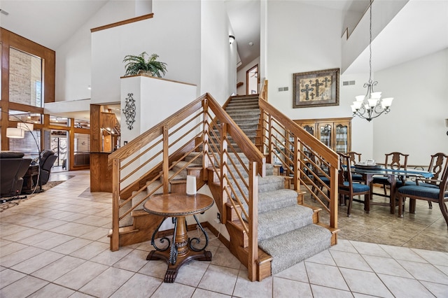 staircase featuring tile patterned floors, visible vents, a high ceiling, and an inviting chandelier