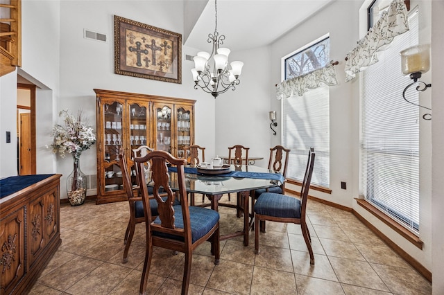 dining space with light tile patterned floors, visible vents, an inviting chandelier, and a towering ceiling