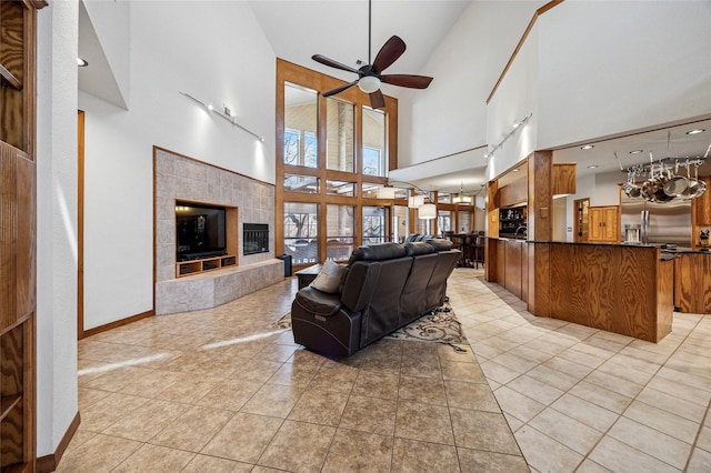 living room with a fireplace, light tile patterned floors, a ceiling fan, and baseboards