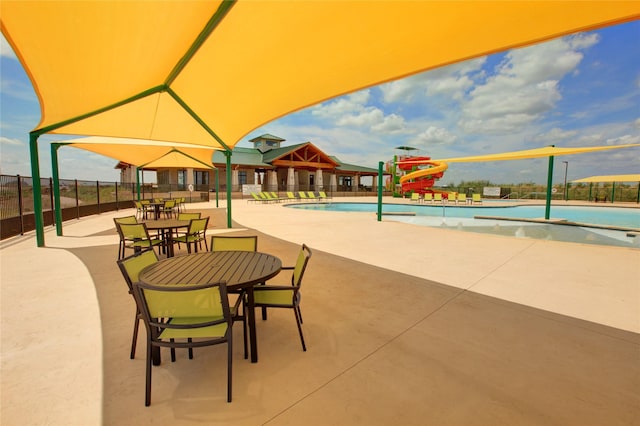 community pool with a patio area and fence