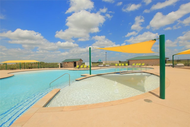 pool featuring a patio area, an outdoor structure, a jacuzzi, and fence