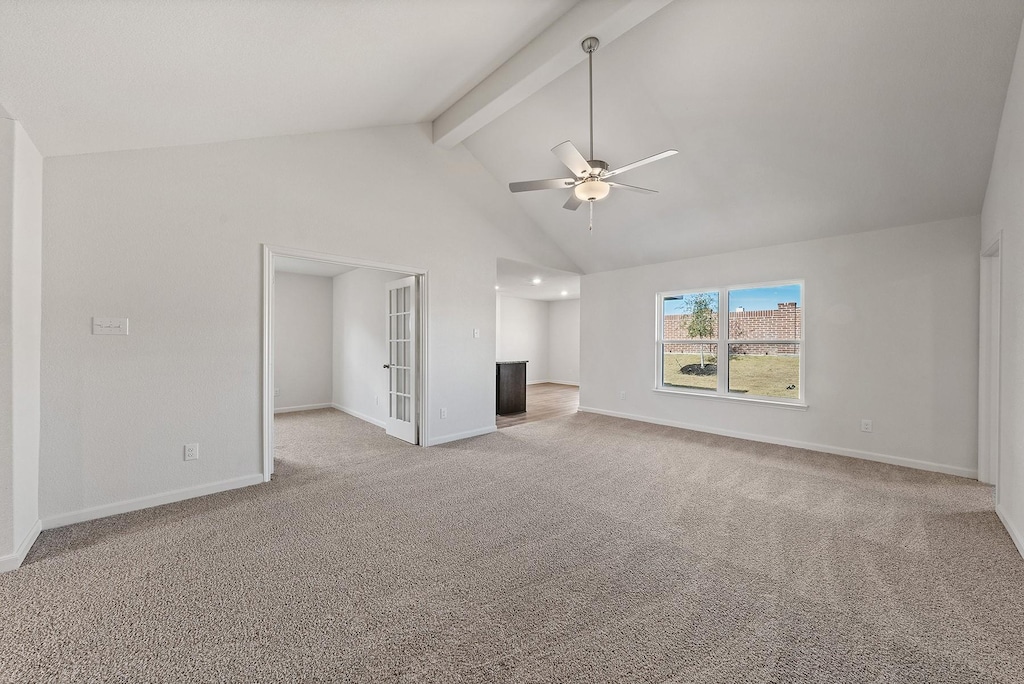 unfurnished living room featuring beamed ceiling, baseboards, light colored carpet, and ceiling fan