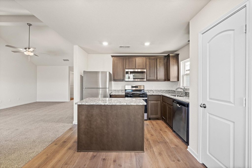 kitchen featuring visible vents, a sink, stainless steel appliances, dark brown cabinetry, and a center island