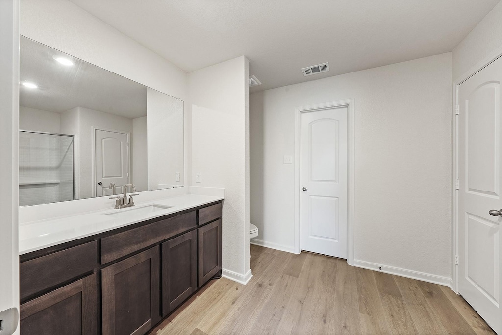 bathroom featuring visible vents, toilet, wood finished floors, baseboards, and vanity