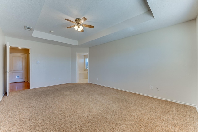 carpeted empty room featuring baseboards, visible vents, a tray ceiling, ceiling fan, and a textured ceiling