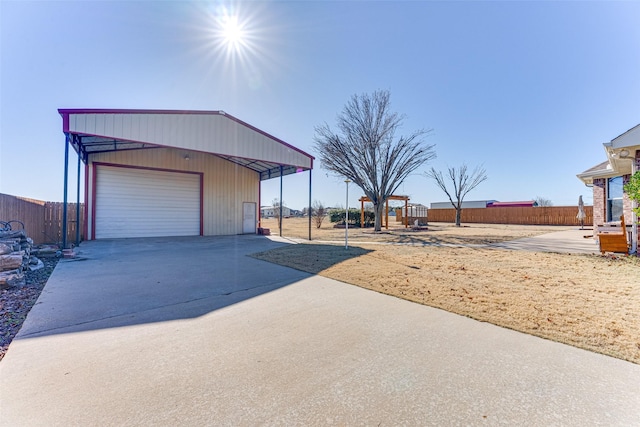 garage with a detached garage, driveway, and fence