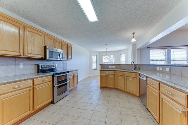 kitchen with a sink, decorative light fixtures, backsplash, appliances with stainless steel finishes, and light tile patterned floors