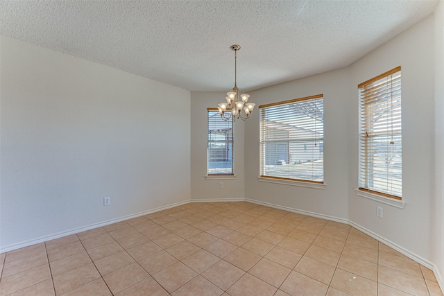 unfurnished room with baseboards, a textured ceiling, and an inviting chandelier