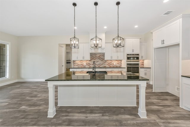 kitchen with double oven, white cabinets, visible vents, and tasteful backsplash