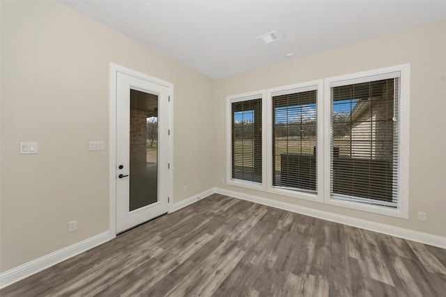 spare room with visible vents, plenty of natural light, baseboards, and dark wood-style flooring