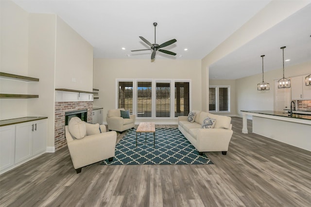 living area with recessed lighting, a fireplace, a ceiling fan, and wood finished floors