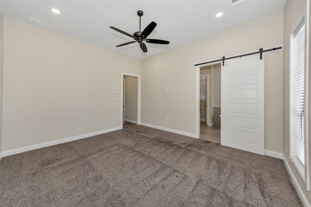 unfurnished bedroom featuring a barn door, recessed lighting, carpet, and baseboards