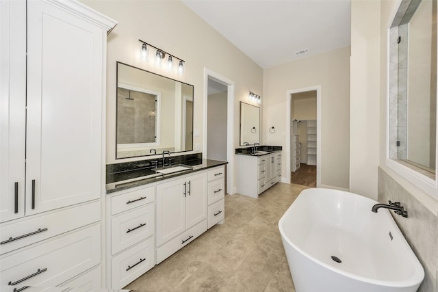 full bath with a sink, visible vents, two vanities, and a freestanding tub