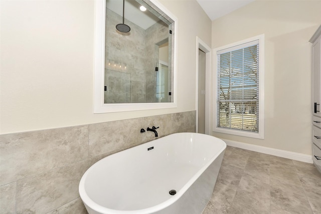 bathroom with a soaking tub, tile walls, and a tile shower