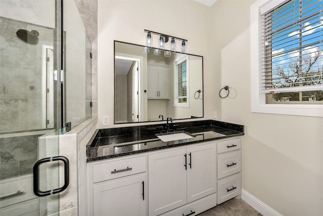 full bath with a stall shower, vanity, and baseboards